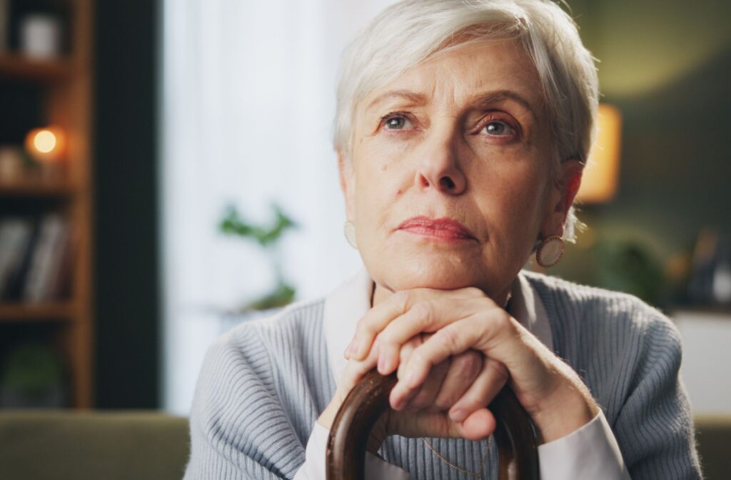 Woman with dementia sitting alone and looking out thoughtfully.