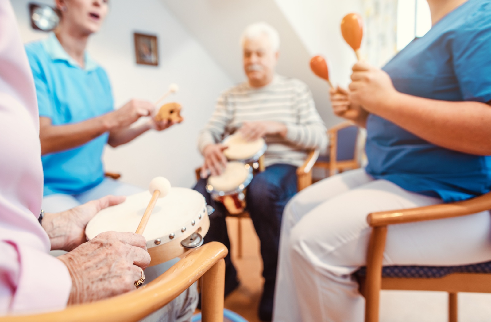 Memory care residents participate in a music therapy session led by a caregiver.