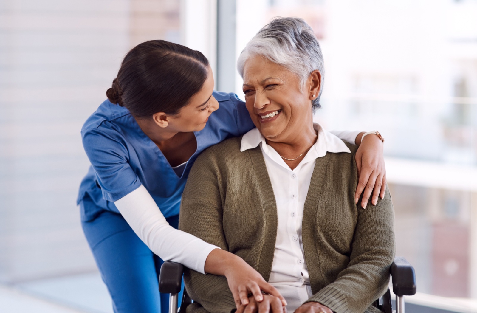 A caregiver embraces a smiling senior resident.