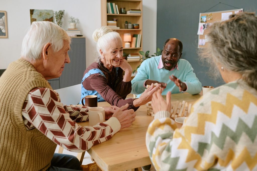 Over shoulder view of senior companions sitting at table screaming happily while looking at falling tower